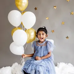 Among the stars for a stylish fifth birthday studio session. The simple grey backdrop with gold stars and balloons allows this little girl's sparkling personality and beautiful blue dress to shine.