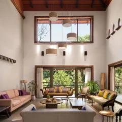 In the formal living room of the Dream Coffee Estate, dappled sunlight fills a space designed for quiet connection. The soaring twenty-foot ceiling, a mix of antique and contemporary furniture, and doors opening to the garden create a sense of timeless repose.