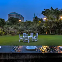 An elegant water feature serves as the tranquil foreground to a lush residential lawn. The gentle bubbling fountains add soothing sound and movement, perfectly complementing the serene evening ambiance and creating an ideal space for relaxation.