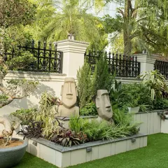 We added a touch of personality to this front garden with unique Easter Island-style sculptures nestled among the plants. The design also features a mature bonsai tree, creating a focal point that is both artistic and natural.