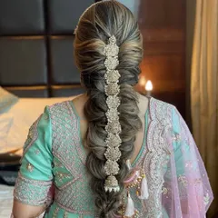 A beautiful, intricate braid with golden accessories woven through it. This is a modern take on the traditional parandi, perfect for a bride who wants a unique and statement making hairstyle.