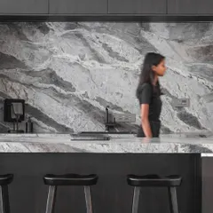 The open kitchen and bar area features a striking grey granite backsplash and countertop. It's a functional space designed for both everyday living and entertaining, continuing the home's monochrome theme.