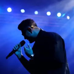 A silhouette against the stage lights tells a story of its own. In these quiet, moody moments, the artist's form becomes an iconic symbol of the music.