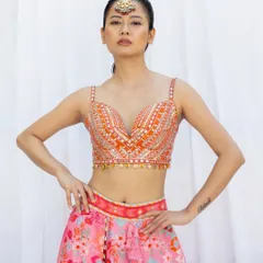 A powerful pose showcasing a beautifully embroidered blouse and a colorful printed lehenga. This is a great example of a clean, commercial-style bridal fashion shot.