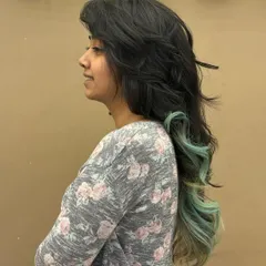 A side profile of a client with long, dark hair and beautiful mint green ends. This is a great example of how to incorporate fashion colors in a subtle yet impactful way.