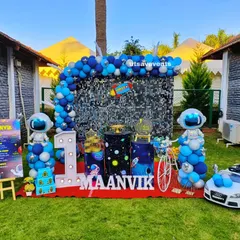 An out-of-this-world space theme for a first birthday, set up outdoors. This decoration includes a shimmering sequin wall, astronaut and rocket cutouts, and a large marquee number '1' to celebrate the big milestone.