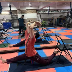 Here, we are using the chair and a yoga belt to work towards Hanumanasana (the splits). This supported variation allows for a gradual and safe opening of the hips and hamstrings.