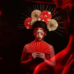 Another angle from our Geisha-inspired creative shoot. The use of dramatic red lighting and shadows adds depth and mystery to the portrait, highlighting the intricate makeup and headpiece.