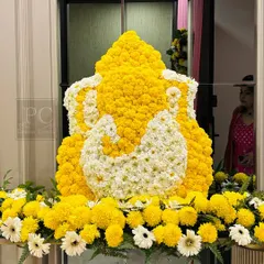 A stunning Ganesha idol crafted entirely from yellow and white flowers. This intricate floral art piece serves as a divine and auspicious centerpiece for a housewarming or religious ceremony.