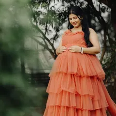 A serene solo shot of the mom-to-be, cradling her baby bump. The soft tulle fabric of the gown looks beautiful against the natural backdrop.