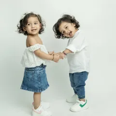 The sweet bond between twins. Holding hands and sharing a smile, this is a moment of pure sibling love.
