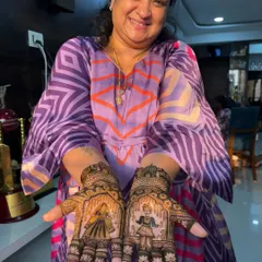 A happy client showing her Gangaur festival mehndi. The design features the traditional figures of Isar and Gangaur on her palms, surrounded by delicate floral patterns.