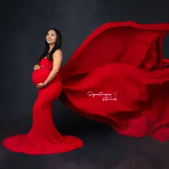 The flowing red fabric creates a sense of motion and drama in this elegant side-profile studio shot.