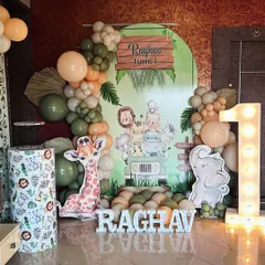 A modern jungle theme for a first birthday. This setup uses muted green and peach balloons, a large marquee number '1', and cute animal cutouts for a stylish take on the safari theme.