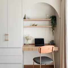 This study space is all about seamless integration. I designed an arched niche with wooden shelves for books and decor, built into a wall that also houses a full-height wardrobe with elegant gold handles.