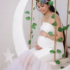 A serene portrait on our moon swing. The all-white outfit and the gentle way she holds her baby bump create a pure and angelic look for her maternity photos.