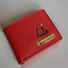 This vibrant red wallet is from my croc-textured series. It's personalized with a nameplate for "Nivi Ram" and a "Love" charm, crafted from durable faux leather.