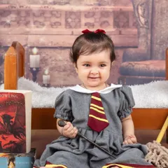 Our little witch is ready for her first year at Hogwarts. The setup includes a fireplace background and a magic wand to complete the look.
