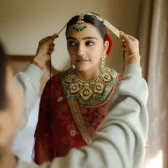 This image captures the final moments of getting ready. You'll learn how to create a classic red bridal look that is both traditional and timeless, complete with a sleek bun and radiant skin.