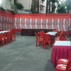 A simple and functional daytime setup for a small gathering. We arranged tables with pink skirting and red plastic chairs, providing a clean and practical space for guests to eat and sit.