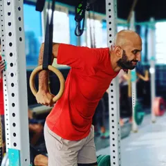 A member performs a ring dip, a more advanced variation that challenges stability. The instability of the rings forces greater muscle engagement through the shoulders and core for a powerful upper body workout.