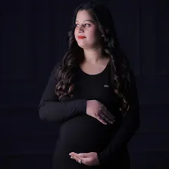 This dramatic portrait uses directional light to sculpt the subject's features and baby bump against a dark background, resulting in a classic and thoughtful image.