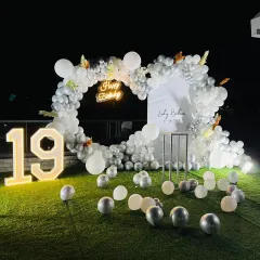 An elegant and chic outdoor setup for a 19th birthday. The heart-shaped balloon frame in white and silver, paired with a "Happy Birthday" neon sign and a large marquee number, creates a perfect photo opportunity on the lawn.