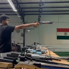 A shooter demonstrates the proper one-handed stance for 10-meter air pistol shooting, a key technique for stability and accuracy.
