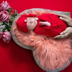 A close-up showing the parents' hands gently holding their newborn, symbolizing protection and love. This pose is a favorite for families wanting to be part of the portrait.
