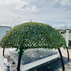 This custom-made gazebo on a terrace is covered with artificial leaves and flowers, creating a unique and permanent shaded structure. It’s a perfect example of a bespoke outdoor feature that requires no gardening.