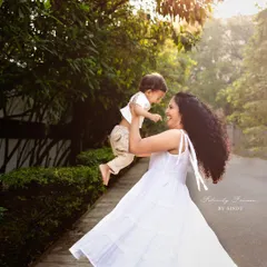 The pure joy of being lifted up by mom. This candid outdoor shot captures a beautiful moment of playfulness and love between a mother and her child.