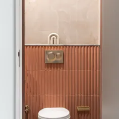Texture takes center stage in this powder room. The fluted terracotta-colored tiles create a stunning feature wall, complemented by the soft, curved lines of the onyx-like panel above.