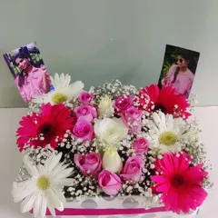 A box full of memories and beautiful blooms. This arrangement features bright pink gerberas, soft pink roses, and personal photos tucked into the flowers, making it a deeply personal and heartfelt gift.