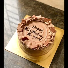 A simple and elegant chocolate truffle birthday cake, topped with chocolate chunks and piped swirls.