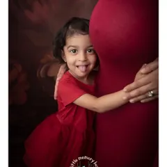 A big sister gives her mum's belly a cheeky hug. Including siblings in maternity shoots is a wonderful way to capture their excitement for the new arrival.