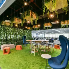 We love bringing the outdoors in. This biophilic breakout zone features an artificial grass floor, unique high-backed chairs, and planters suspended from the ceiling, creating a refreshing park-like atmosphere right inside the office.