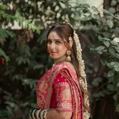 A symphony of love and tradition. This bride's look features a soft, romantic makeup style with a beautiful long hairstyle adorned with fresh flowers, perfect for her pink bandhani saree.