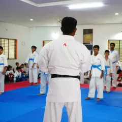 A black belt instructor referees a sparring session, ensuring safety and fair play among the students.