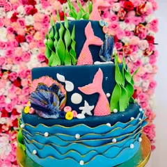 Dive into a magical celebration with this multi-tiered mermaid theme cake. It’s decorated with handcrafted fondant seaweed, shells, and mermaid tails, creating an enchanting underwater scene perfect for a fantasy-themed birthday.
