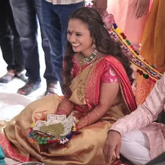 A bride receiving blessings during her Ganesh Poojan. Her look is inspired by the divine grace of Radha, with soft makeup and a traditional saree.