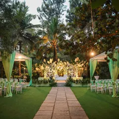 An evening wedding reception at Farmhouse Collective, showcasing the beautiful aisle and stage lit up against the twilight sky. The green drapery adds a touch of color to the natural surroundings.