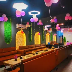 A simple yet effective decoration for a cafe party. Bunches of pink and purple balloons are hung from the ceiling, adding a festive touch to the entire space.
