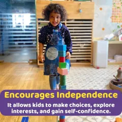 A young girl proudly stands by the tall tower she built. Activities like block building encourage independence, problem-solving, and give a great sense of accomplishment.