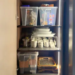 This cabinet uses clear bins to group items like groceries, snacks, and green tea. Below, we've used a riser to double the storage space for plates and cups, making everything visible.
