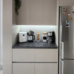This image shows the adjacent pantry or coffee station, designed to match the crockery unit. It provides a dedicated space for small appliances with handle-less drawers below for concealed storage.