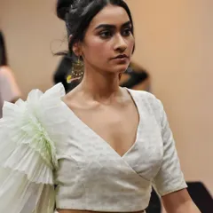 A backstage moment with a model wearing our signature ruffled sleeve blouse. This close-up highlights the texture of the fabric and the unique silhouette of the sleeve.