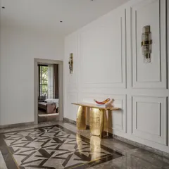 An entrance designed with restraint and clarity. The foyer features a stunning geometric marble inlay on the floor, a sculptural gold console table, and elegant wall sconces, reflecting the essence of minimal yet luxurious interiors.