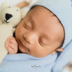 A close-up showing the baby's peaceful face as he cuddles a tiny knit bear. These detail shots highlight the innocence and serenity of your newborn.