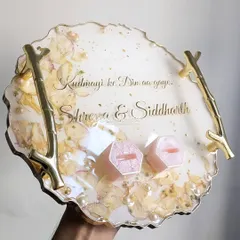 This engagement ring platter was created with a couple's special song lyrics and flowers from a cherished memory. The delicate dried flowers and pearls are preserved in clear resin, with elegant branch-style handles and custom ring holders.