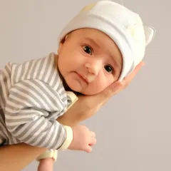 A beautiful portrait of an awake newborn resting in their parent's hand. The direct eye contact and curious expression make for a captivating and intimate image.